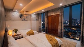 Een moderne slaapkamer met twee bedden, stadszicht en een ruime kledingkast.