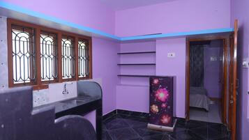 A room with a black tiled floor, a window with metal bars, a sink, a cabinet with a floral design, and a door leading to another room.