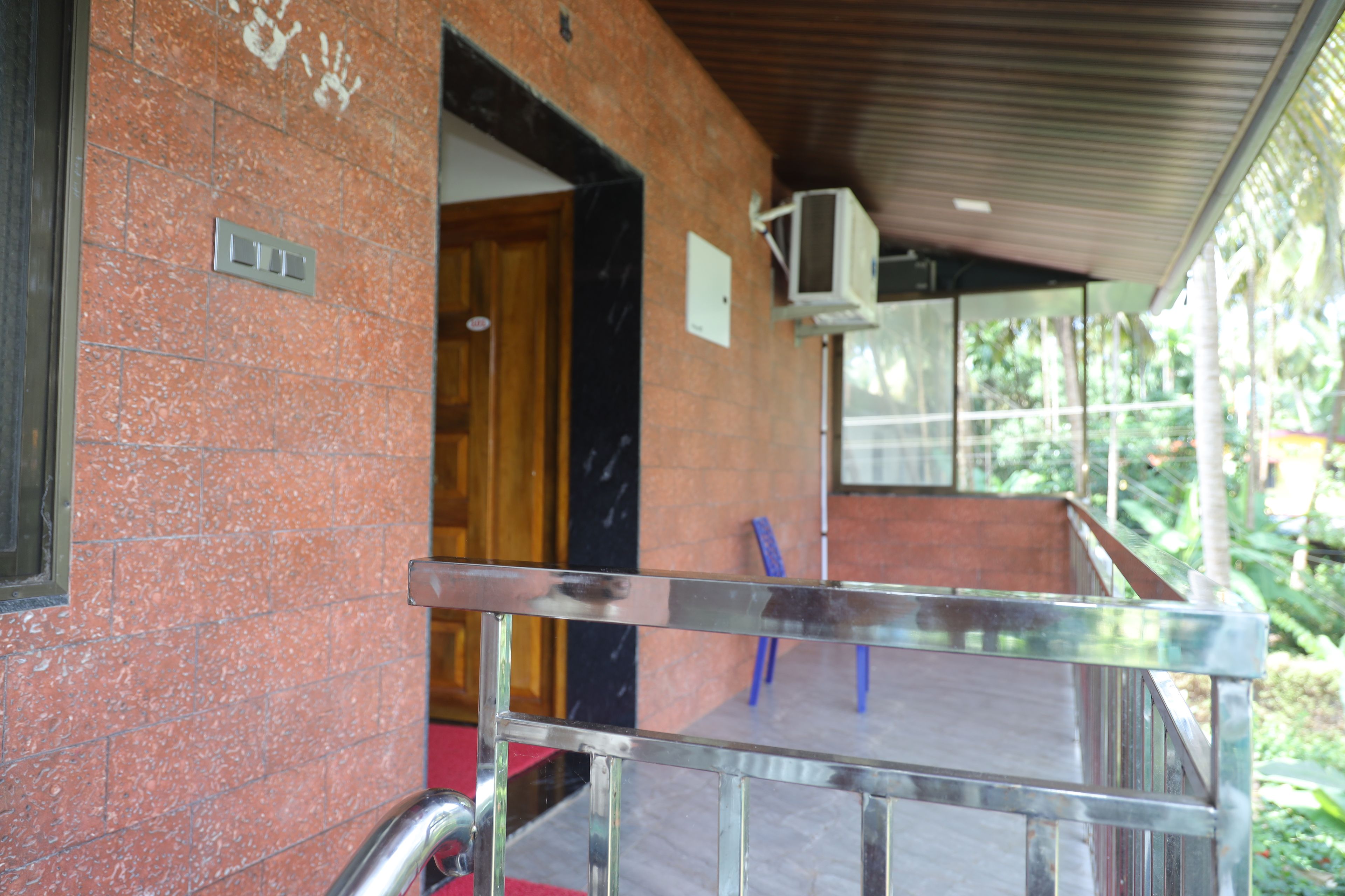 Una entrada de edificio con un portón metálico, una puerta de madera y un muro con baldosas.