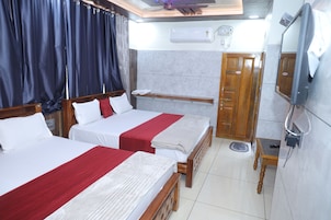 Habitación de hotel con dos camas, televisión y puerta de baño.