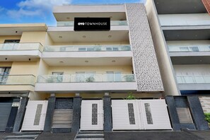 A multi-story residential building with balconies, a sign reading 'OYO TOWNHOUSE,' and gated entrances. - Townhouse Hotel Sec- 54 Golf Course Road (Gurugram)