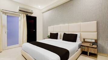 Habitación de hotel con una cama grande, una mesita de noche, un equipo de aire acondicionado y una puerta con cortinas.