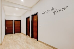A hallway with three wooden doors, each marked with a number, leading to a second-floor area. - Townhouse Hotel Sec- 54 Golf Course Road (Gurugram)
