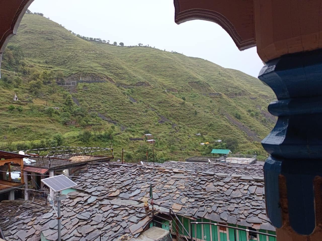 A mountainous landscape with a terraced area and a building with a green roof.