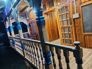 Interior de fusta amb barana de balcó, una porta amb mosquitera i un mur amb dibuix de reixeta.