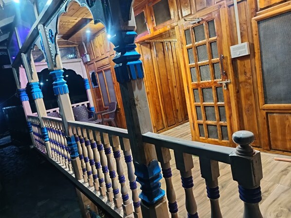 A wooden interior with a balcony railing, a door with a mesh screen, and a wall with a grid pattern.