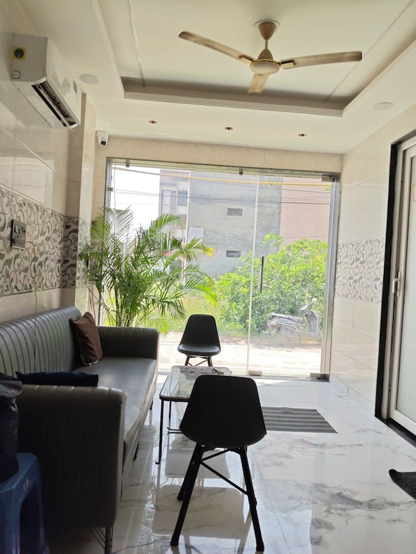 A modern living room with a sofa, a chair, a coffee table, and a ceiling fan. - SRG Hotel and Restruant (Mathura)