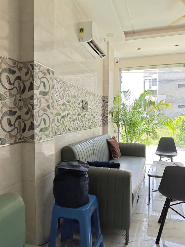 A modern interior with a sofa, a small table, and a blue stool. - SRG Hotel and Restruant (Mathura)