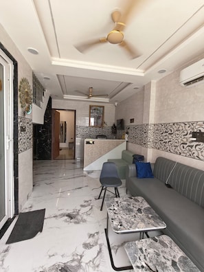 A modern interior with a sofa, a dining table, and a ceiling fan. - SRG Hotel and Restruant (Mathura)