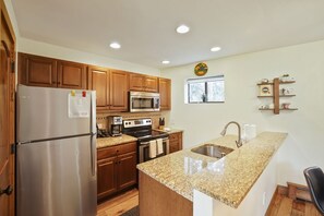 A modern kitchen with wooden cabinets, stainless steel appliances, granite countertops, and a window with a view. - C8 Cornerstone Condos 3 Bedroom Condo (Avon)