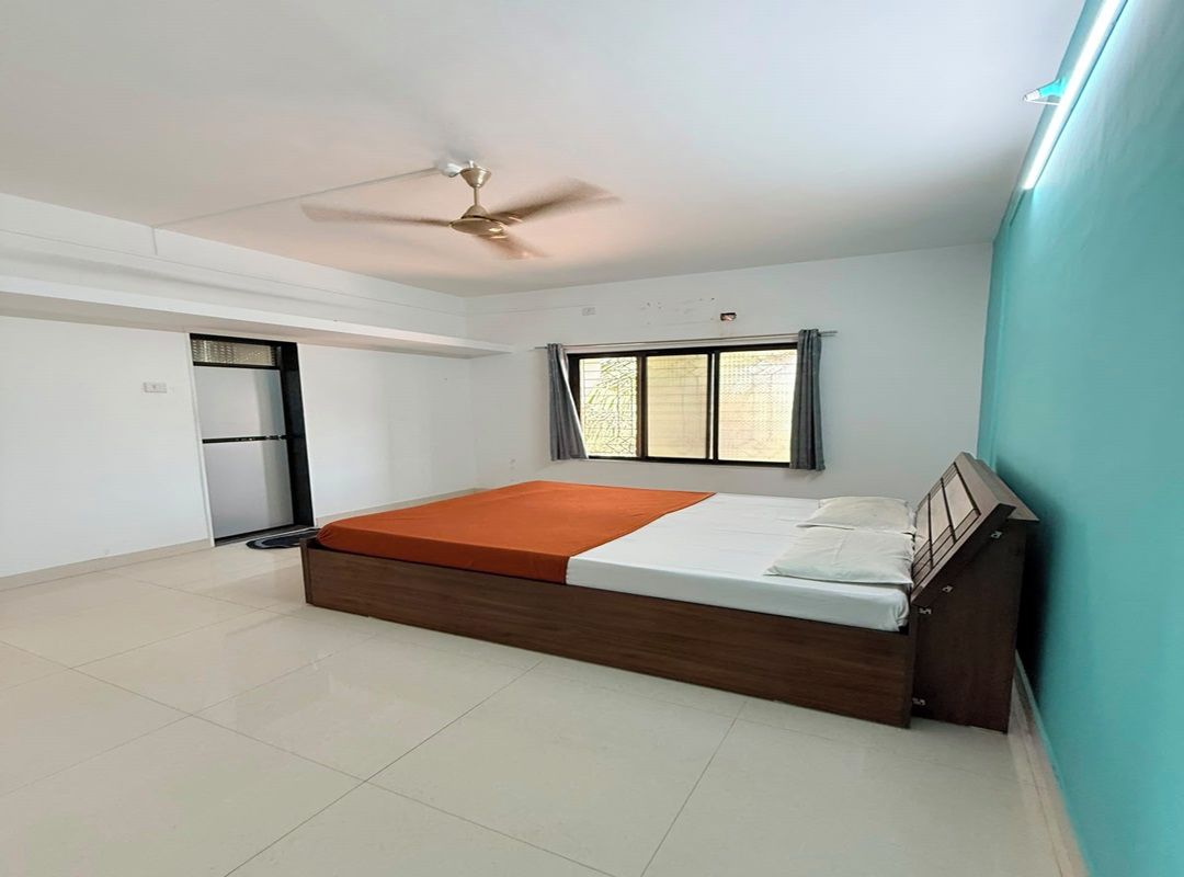 A bedroom with a bed, a ceiling fan, a window with curtains, and a door leading to another room.