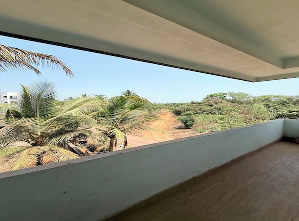 A room with a view of a dirt path and palm trees.