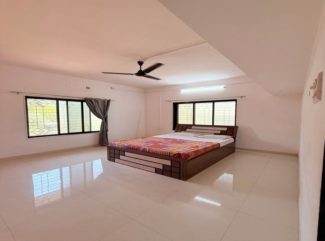 A bedroom with a bed, ceiling fan, and large windows.