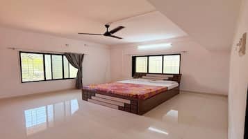 Un dormitorio con cama, ventilador de techo y ventanas amplias.
