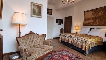 Een traditionele slaapkamer met een groot bed, een klassieke fauteuil en een houten vloer.