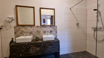 Een badkamer met twee wastafels, een douche en een spiegel met gouden lijst.