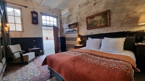 Ein Schlafzimmer mit einem Bett, einem Sessel, einem Nachttisch, einer Lampe und einem Bild an der Wand.