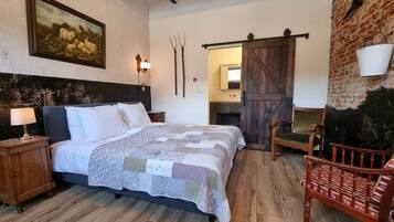 Een slaapkamer met een bed, nachtkastje, stoel, houten wand en een deur.