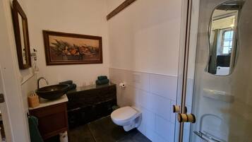 Een badkamer met een wastafel, spiegel, toilet en douche.