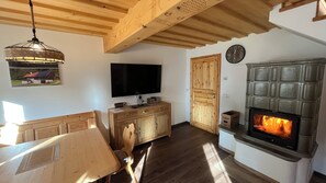 A wooden interior with a television, a fireplace, and a dining area. - Holzer Vacation Home (Mönichwald)
