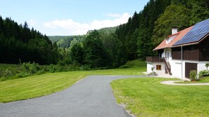 A house with a sloped roof, solar panels, and a paved driveway leading to the entrance. - Holzer Vacation Home (Mönichwald)