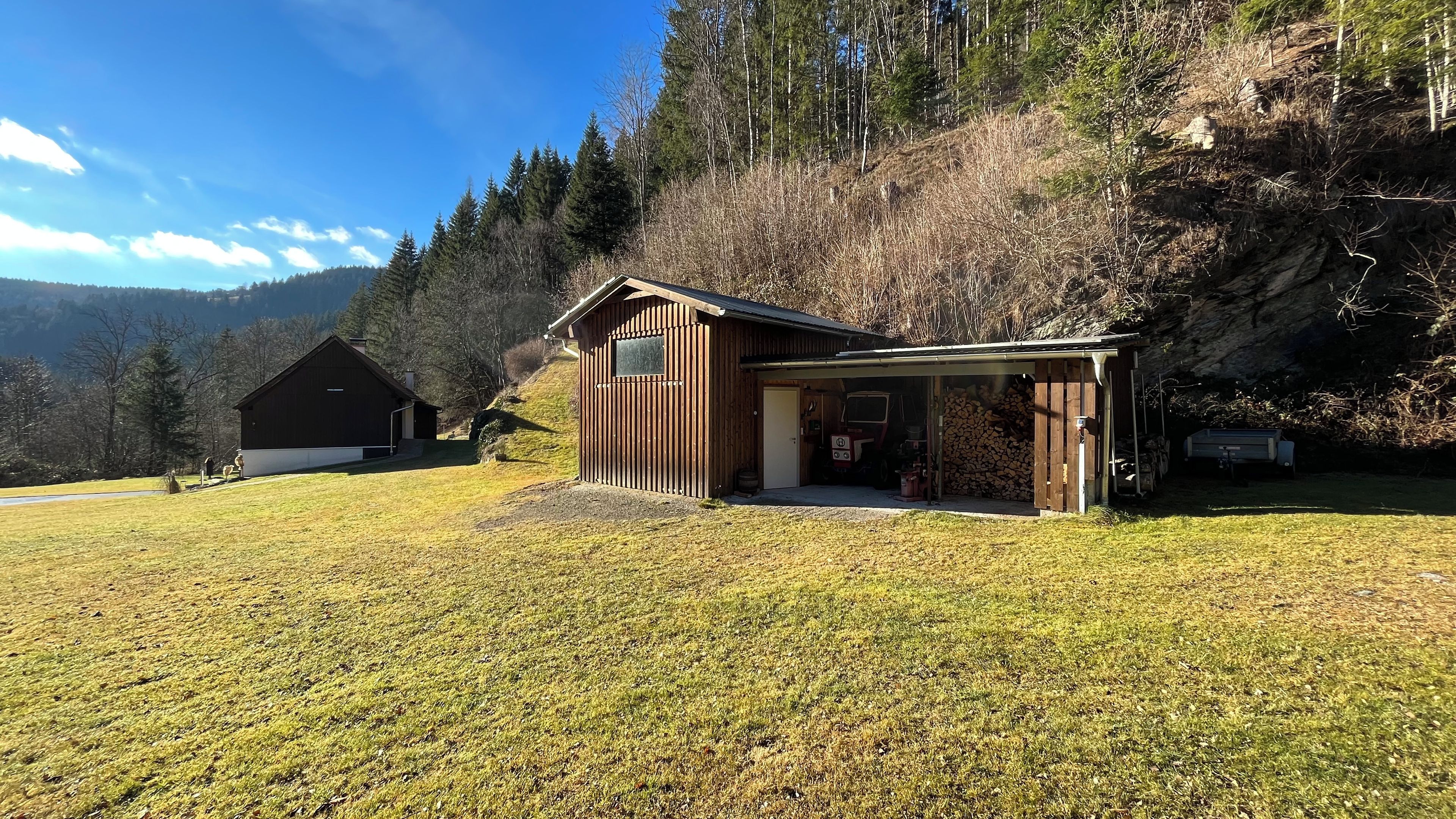 Ein rustikales Blockhaus mit überdachter Veranda, einer separaten Garage und Bergblick.