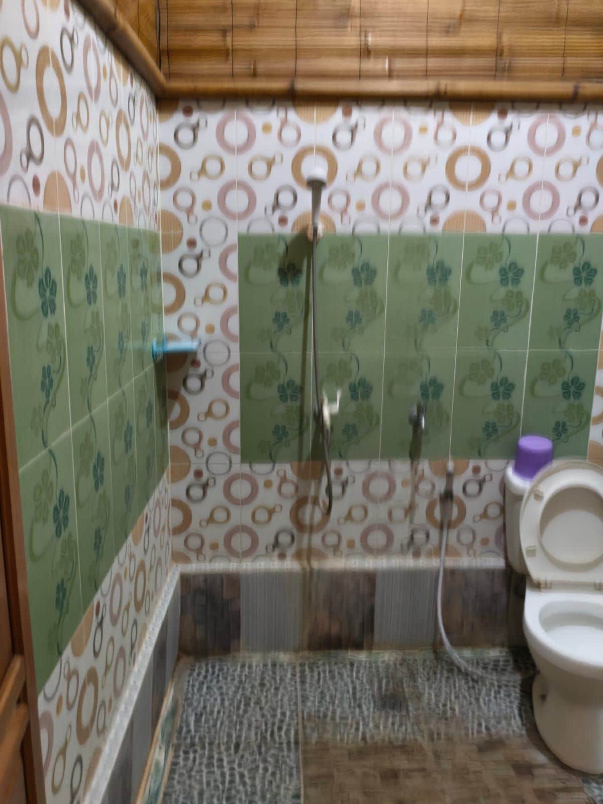 A bathroom with patterned tiles, a shower, a toilet, and a towel rack.