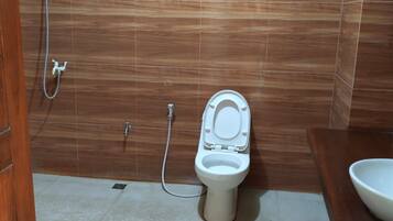 A bathroom with a toilet, a shower, and a sink.