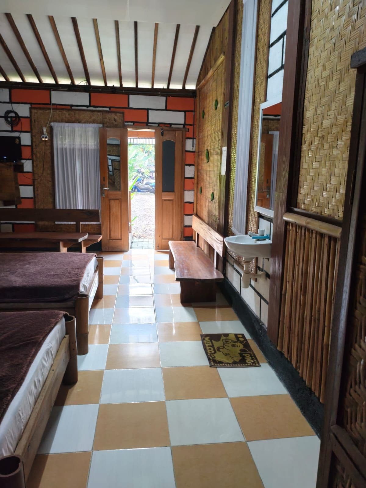 Una habitación con dos camas, un banco, un lavamanos y vistas al exterior.
