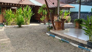 A covered outdoor area with a gravel floor, wooden structures, and potted plants.