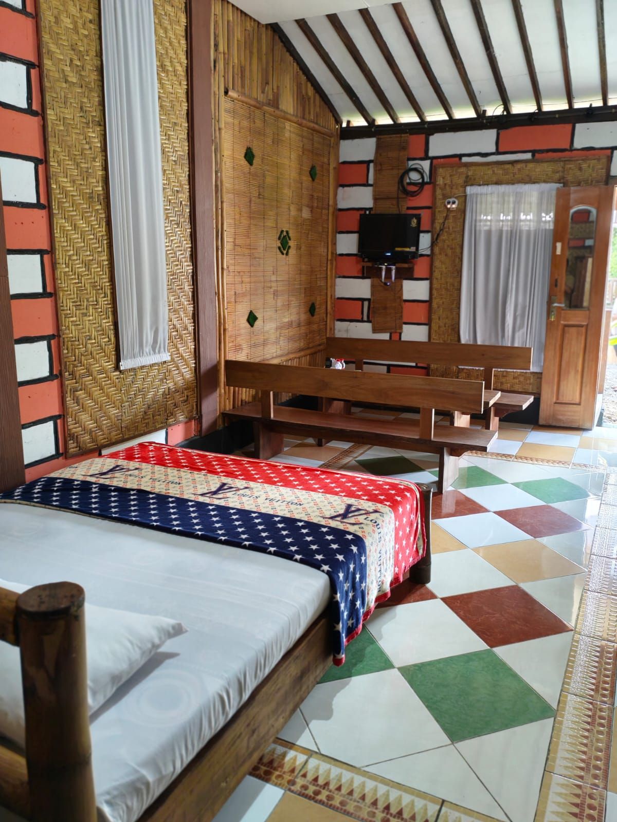 Una habitación con cama, muebles de madera, un televisor y suelo estampado.