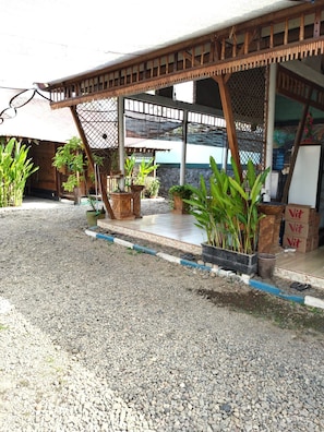 A building with a covered outdoor area, potted plants, and a gravel ground. - Hotel O Banyu Asem Residence (Banyuwangi)