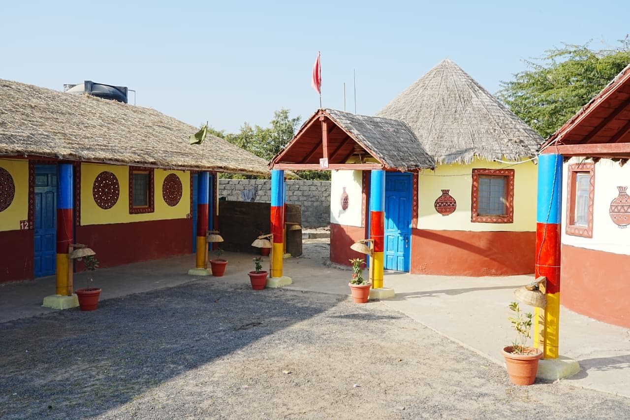 Un patio con edificios tradicionales, algunos con techos de paja, y plantas en macetas.