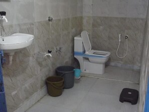 Bany amb rentamics, vàter i plat de dutxa. Hi ha papereres i un tamboret.