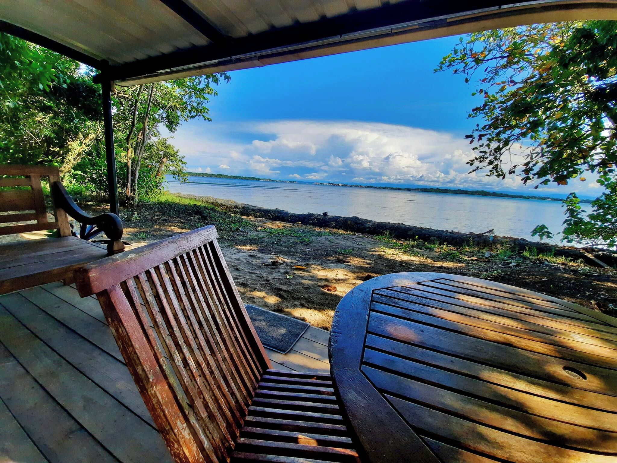 Terraza de madera con un banco y una mesa con vistas a un cuerpo de agua.