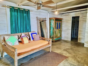 A rustic room with a wooden sofa, a woven rug, a mirror, and a green curtain. - Incredible loft on the Beach! (Big Creek)