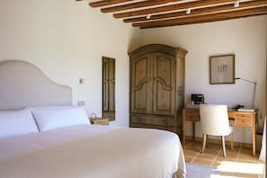 Un dormitorio con una cama, un armario de madera, un escritorio con silla y una lámpara.