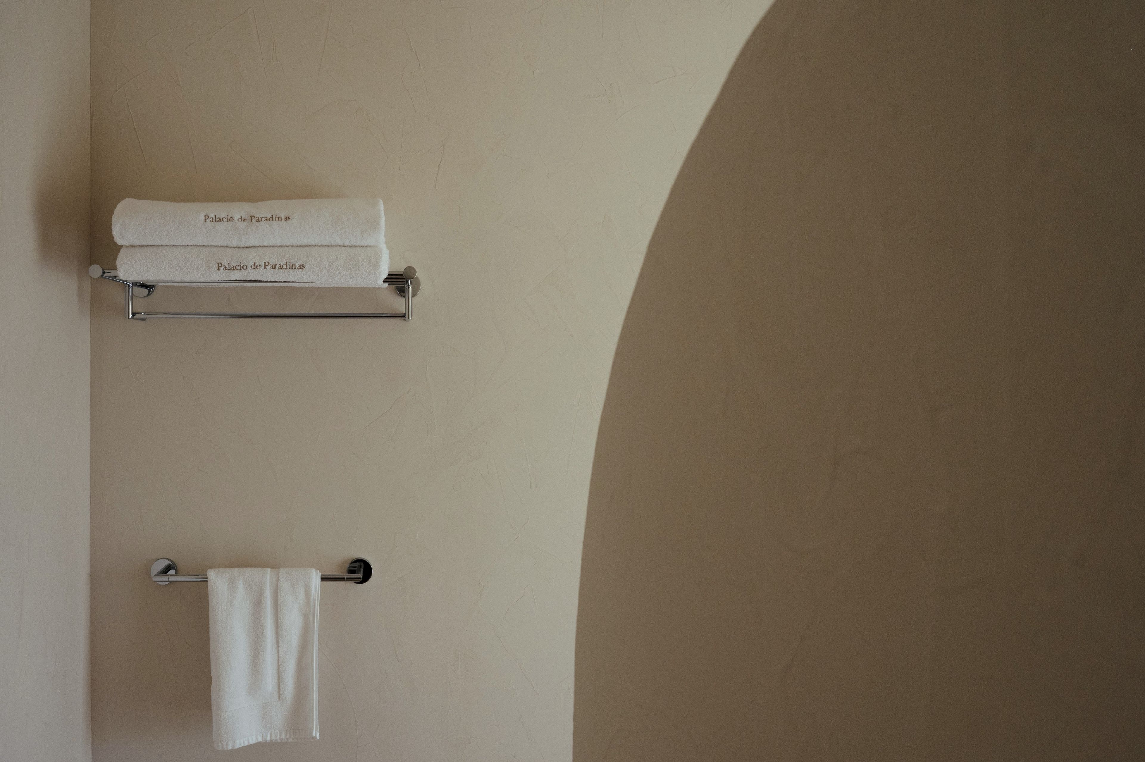 Une salle de bain avec un porte-serviettes sur lequel sont posées deux serviettes blanches, dont l’une est étiquetée « Palacio de Paradinas ».
