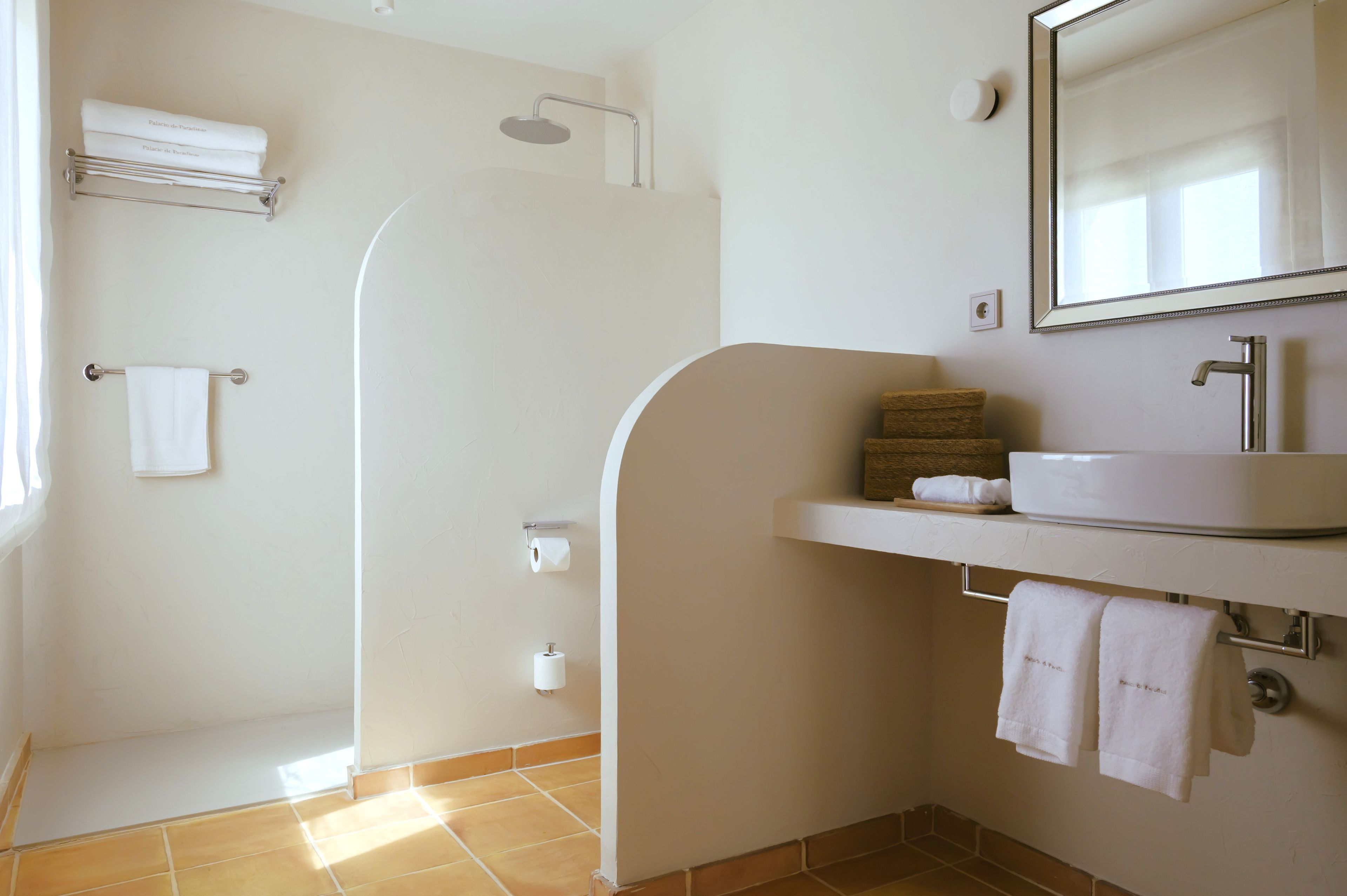 Une salle de bain équipée d’une douche, d’un lavabo, d’un miroir et de serviettes.