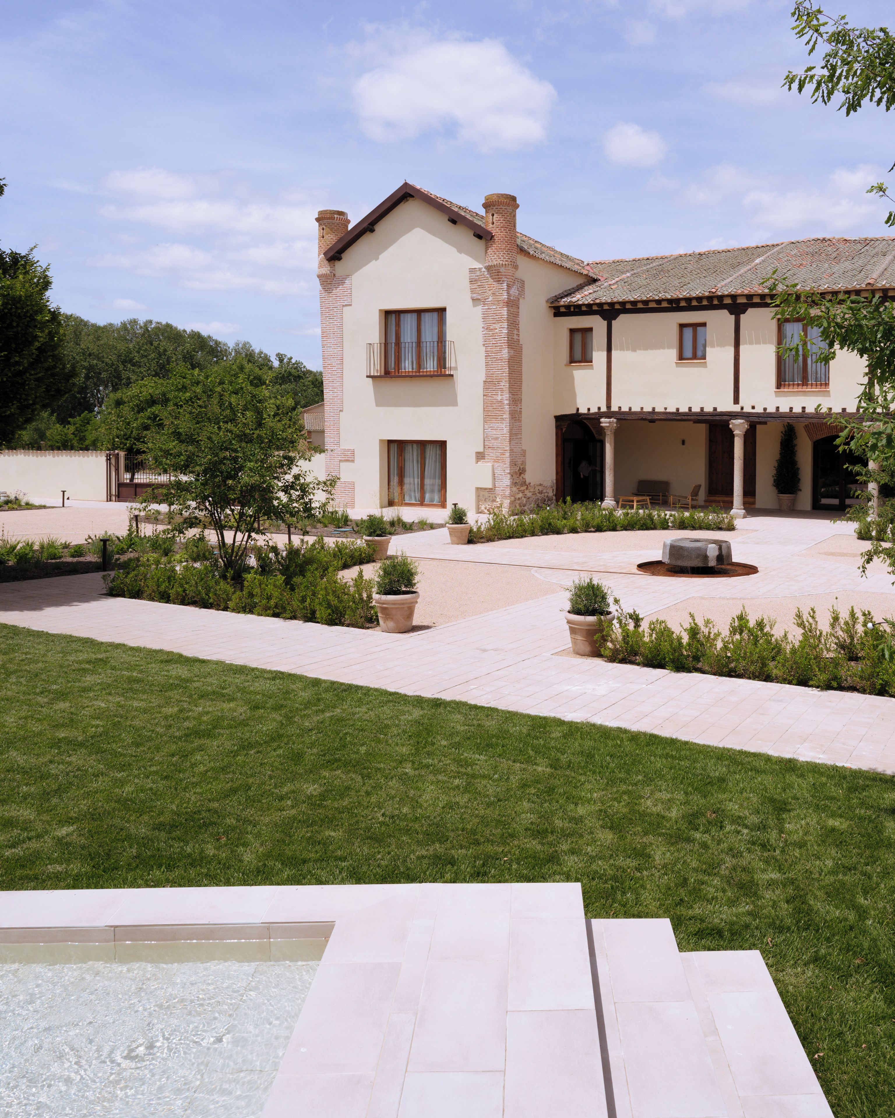 Une maison à deux étages avec une cour, une piscine et un jardin bien entretenu.