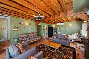 A cozy living room with wooden beams, a patterned sofa, and a fireplace. - Lake View Cabin Game Room (Crestline)
