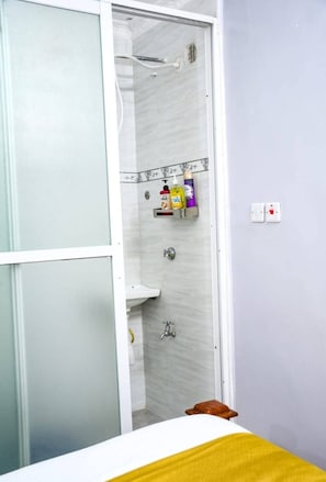 A bathroom with a shower, a sink, and a toilet. There are toiletries on a shelf. - Naivasha - Gateaway View Palace  (Naivasha)