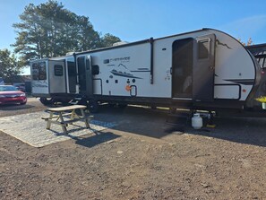 A mobile home with a covered patio area, a picnic table, and a propane tank. - Russells River Retreat (Gadsden)