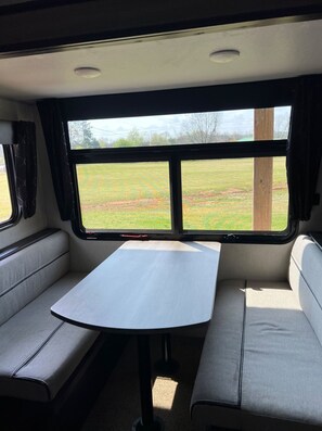 A compact RV interior with a table and two seating areas. - Russells River Retreat (Gadsden)
