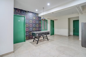 A corridor with green doors, a foosball table, and a patterned wall. - Townhouse DLF Phase-4 MG Road Cyber Hub (Gurugram)