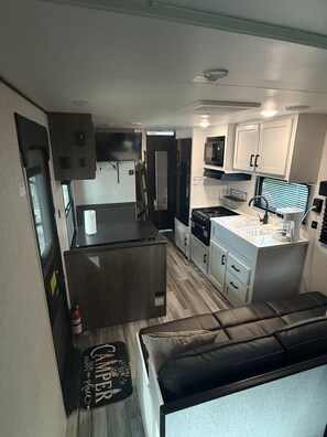 A compact kitchen with a stove, microwave, and sink. - River Rockin' Retreat (Gadsden)