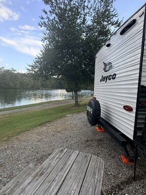 A Jayco RV parked by a lake with a wooden deck in front. - River Rockin' Retreat (Gadsden)