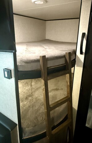 A bunk bed with a ladder in a small, enclosed space. - River Rockin' Retreat (Gadsden)