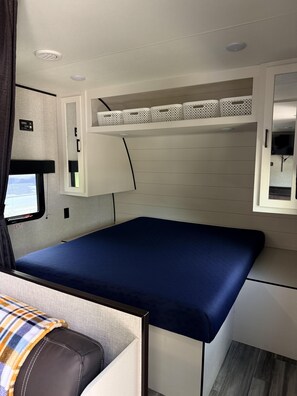 Ein kompaktes Wohnmobil-Interieur mit einem Bett, Stauraumschränken und einer kleinen Sitzecke.