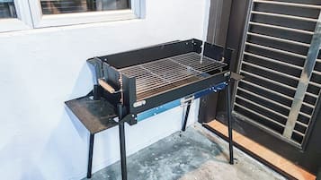 A barbecue grill positioned against a wall with a window and a door.